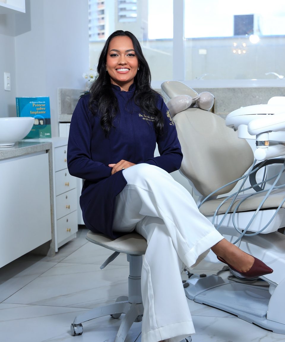 Dra. Fernanda Karoliny sentada em seu consultório odontológico